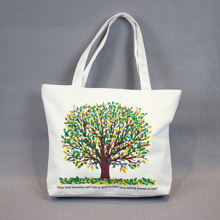 White canvas tote bag with colorful tree graphic and decorative leaf text along bottom