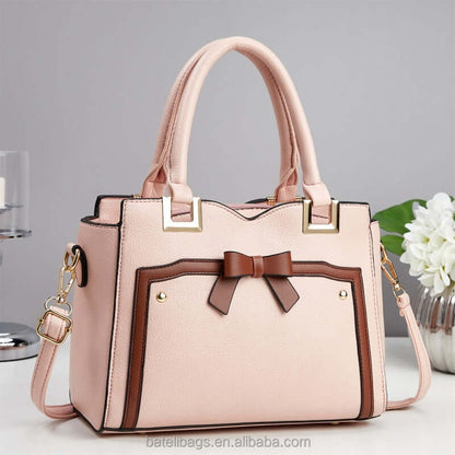 Pink commuting shoulder bag with bow detail, gold hardware, and crossbody strap