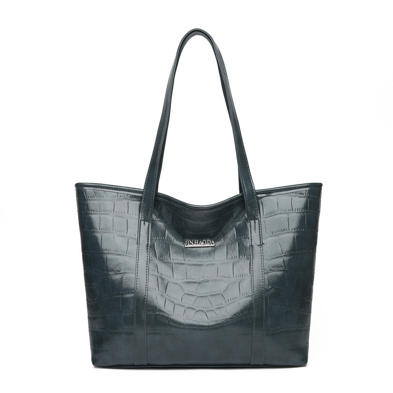 Large dark green croc-embossed tote bag with top handles and front logo patch