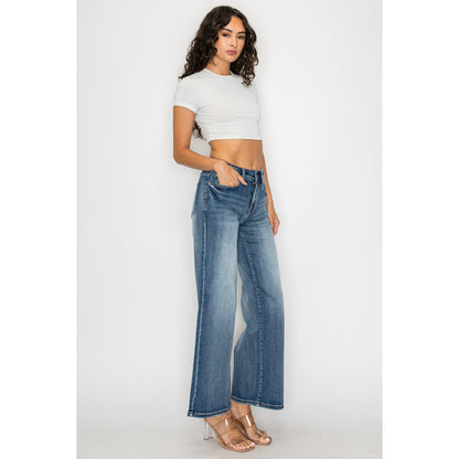 High-waisted flare jeans in medium blue wash, worn by model standing front with wide legs.