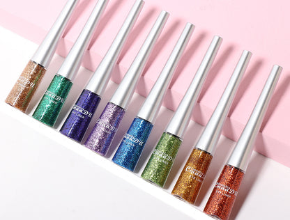 Set of glittery lip glosses with metallic applicators on a pink background
