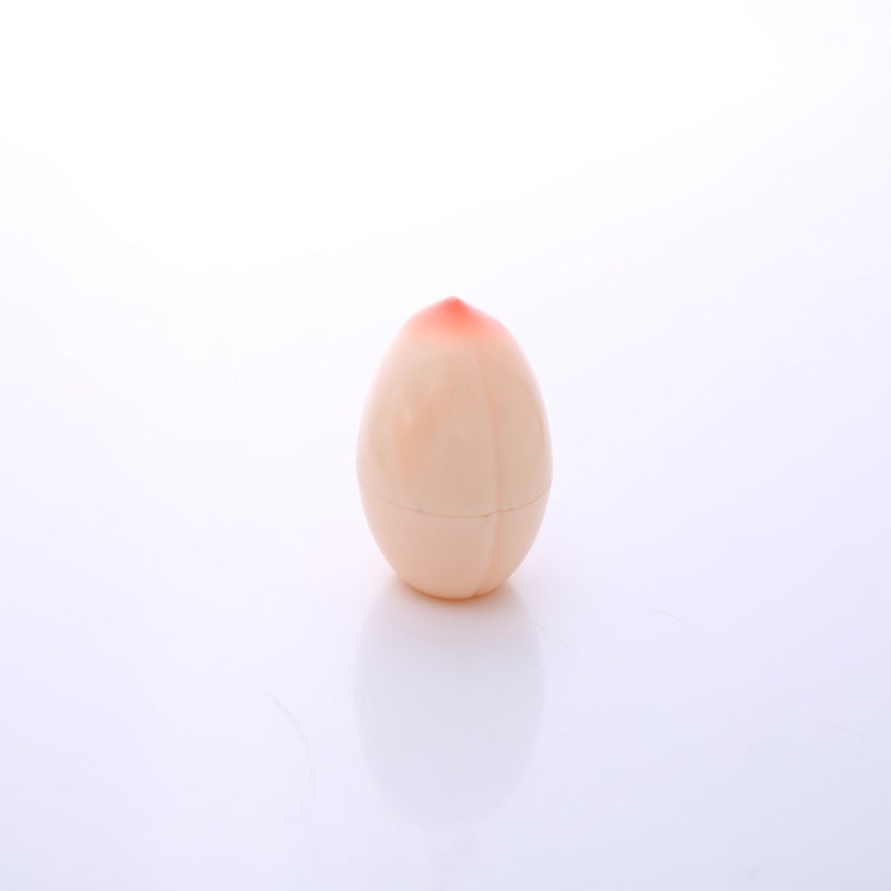 Wooden egg with a small pinkish object on top against a white background