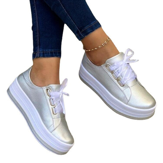 White sneakers worn with blue jeans on a white background