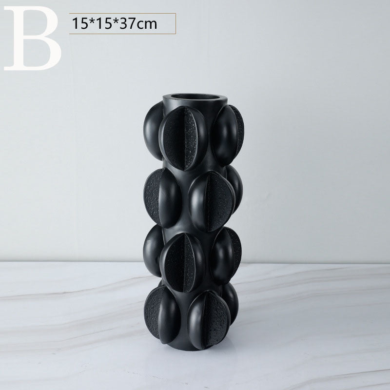 Sculptural black resin vase with tall stacked oval pods and circular top opening