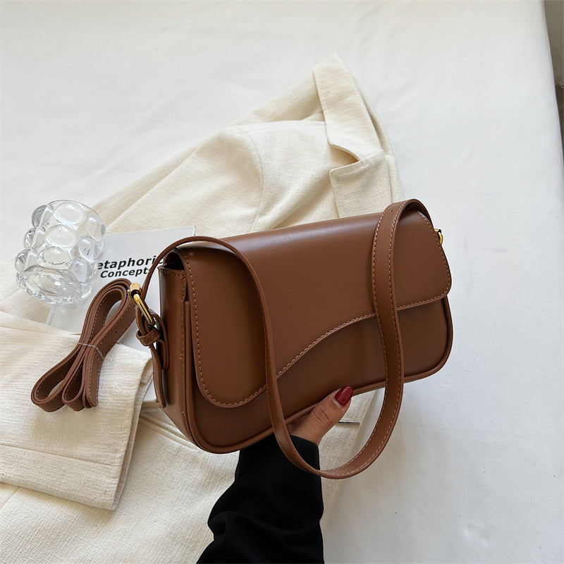Light brown flap shoulder bag with magnetic buckle, curved flap and adjustable strap