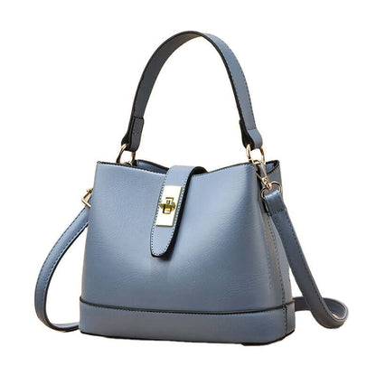 Light blue tote handbag with short handles, shoulder strap, and gold clasp