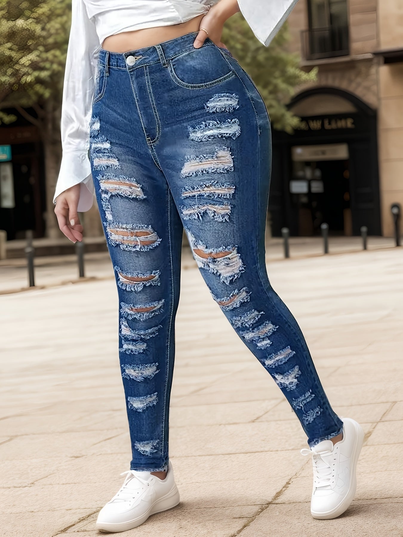 Women's blue ripped skinny jeans, front view with thigh and knee distressing