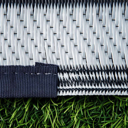 Reversible outdoor rug texture with dark woven surface and light edge binding