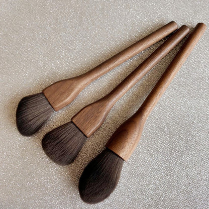 Set of four wooden makeup brushes with brown bristles on a textured beige background