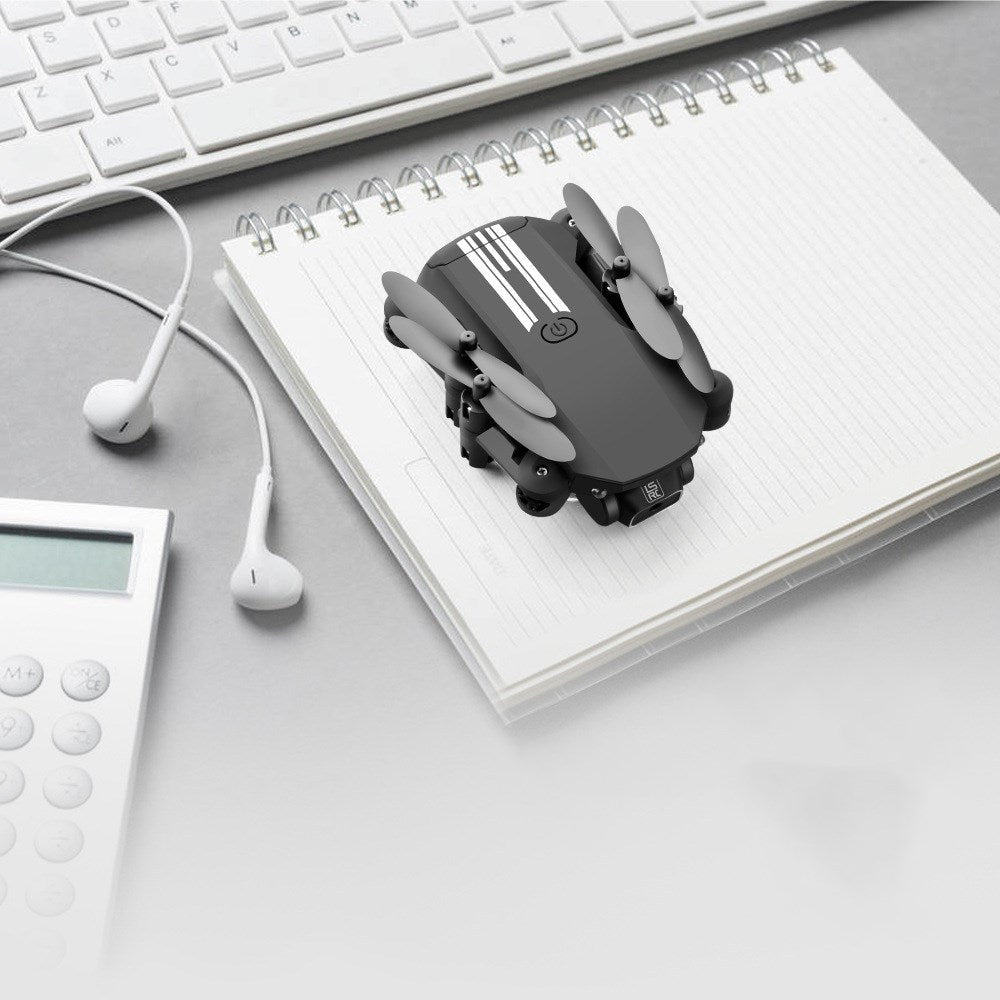 Black and gray device on a notebook with a keyboard, calculator, and earphones in the background