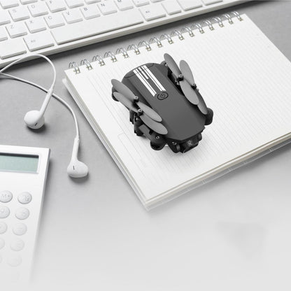 Black and gray device on a notebook with a keyboard, calculator, and earphones in the background