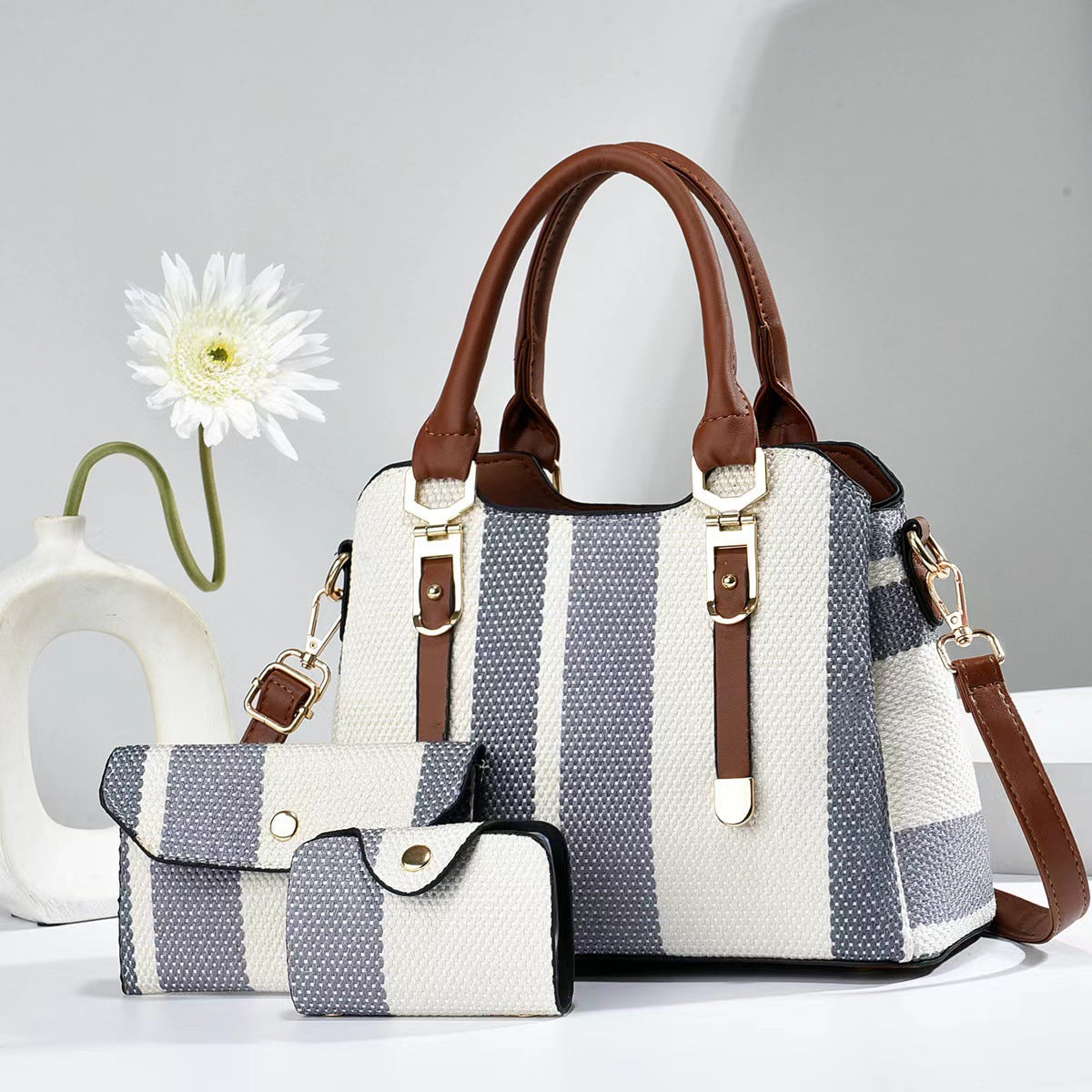 Large white and blue striped canvas crossbody bag with brown handles and matching pouch bags.