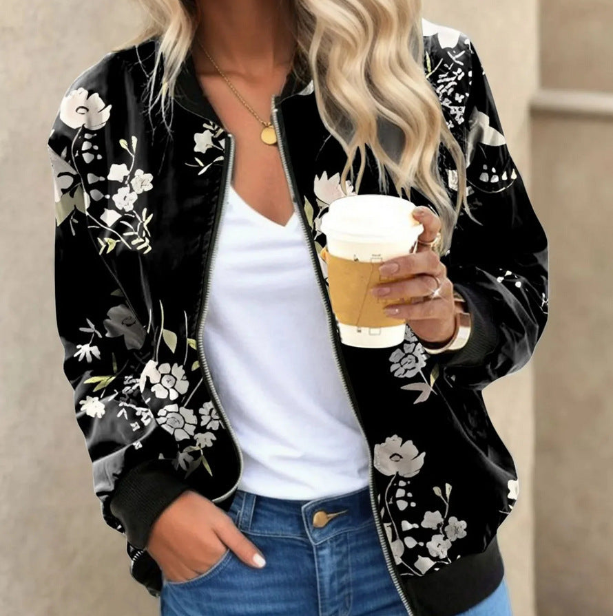 Person wearing a black floral bomber jacket holding a coffee cup.