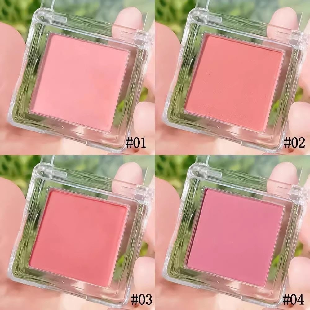 Four square blushes in clear cases held by a hand with a green outdoor background.