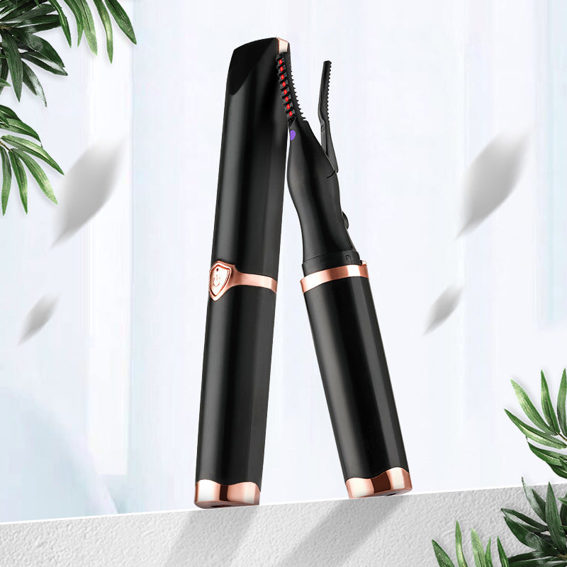 Black and rose gold eyelash curler on a light background with green leaves