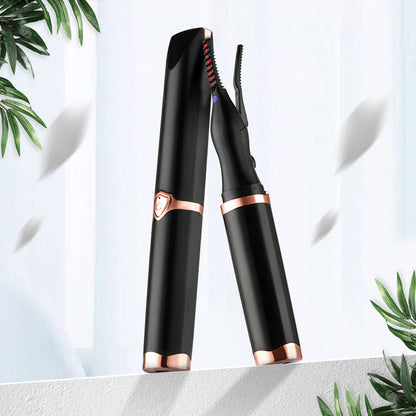 Black and rose gold eyelash curler on a light background with green leaves