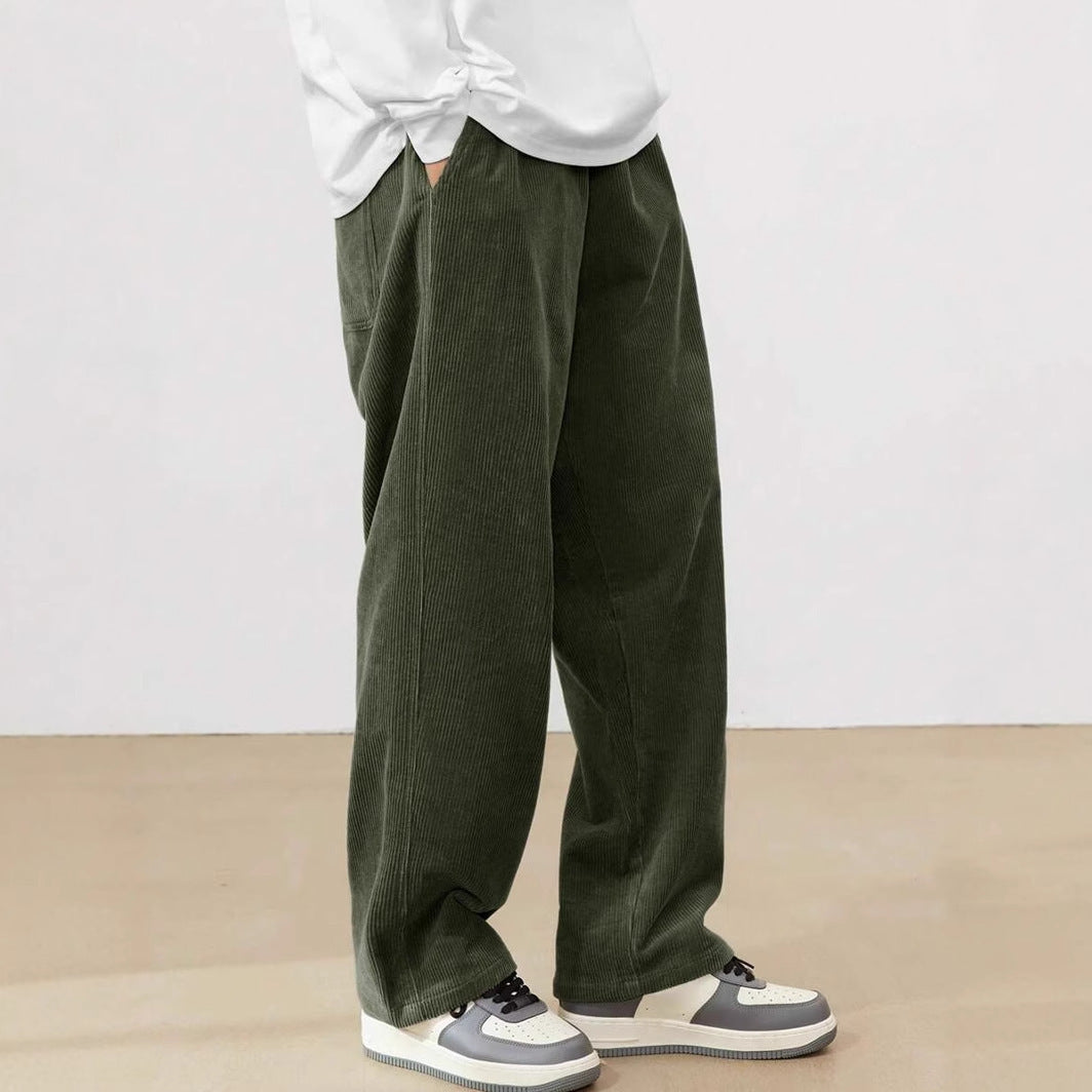 Person wearing green wide-leg pants and a white shirt on a plain background