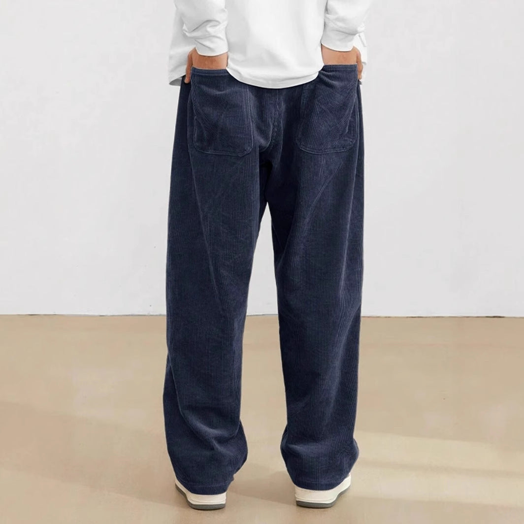 Person wearing navy blue pants and a white shirt on a plain background