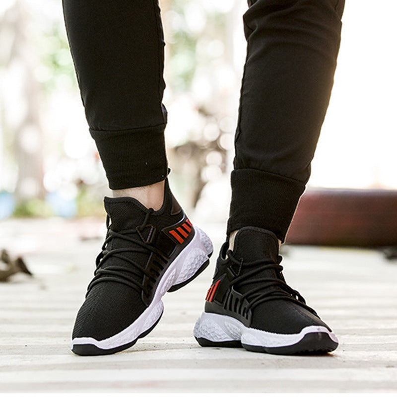 Black sneakers with red accents worn by a person on a blurred outdoor background