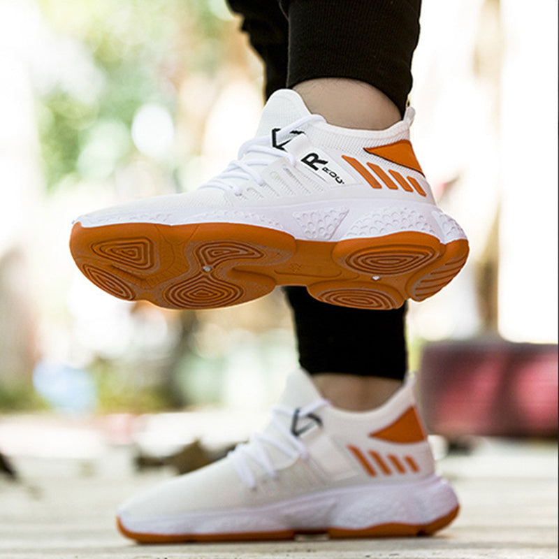 White and orange athletic shoes with brand logo on a blurred outdoor background