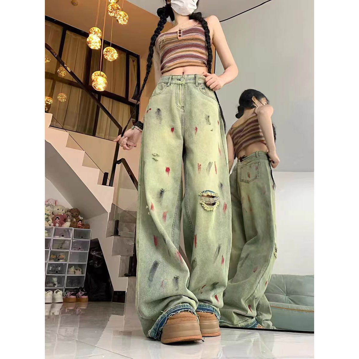 Person wearing distressed light green jeans and a striped crop top in an indoor setting.