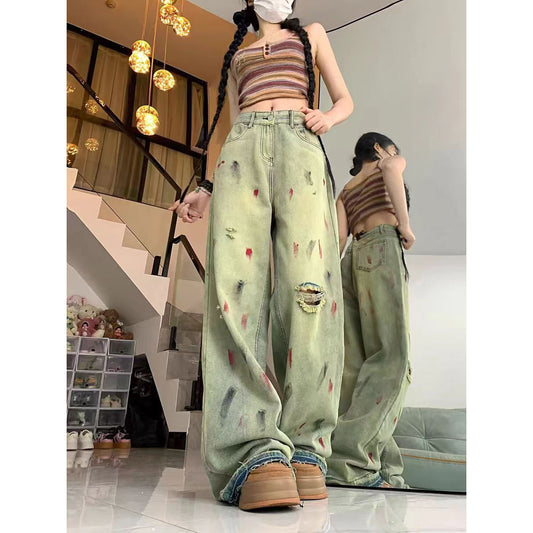 Person wearing distressed light green jeans and a striped crop top in an indoor setting.