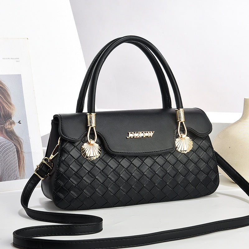 Women’s crossbody handbag in black with woven pattern, top handle, and tassel charm details.