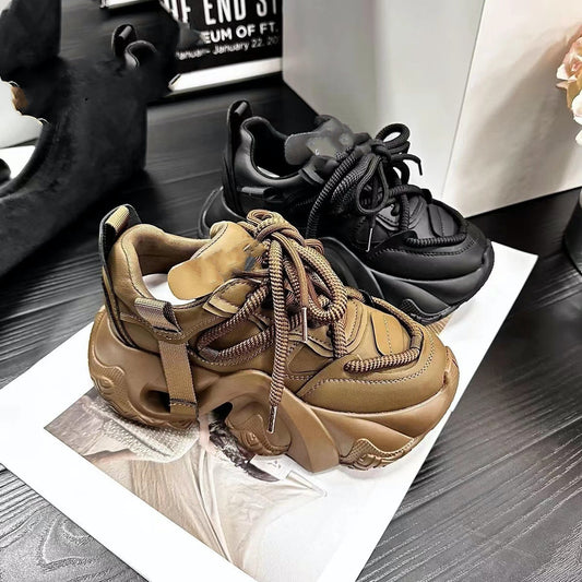 A pair of women's sneakers with thick soles and lace-up closure, displayed in a store setting, with one sneaker in brown color and the other in black color.