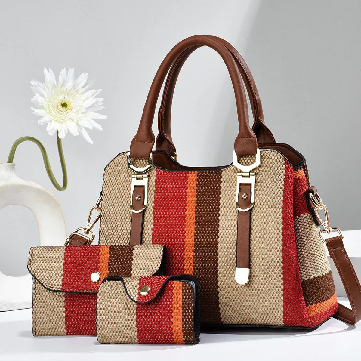 Large canvas crossbody bag with red and brown striped panels, brown handles, and two zipper pouches.